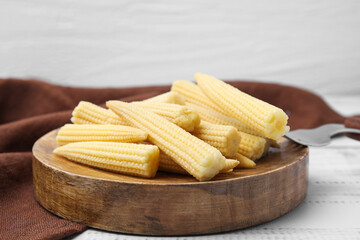 Pickled baby corn and fork on white wooden table, closeup