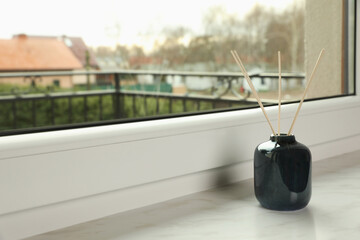 Aromatic reed air freshener on windowsill indoors, space for text