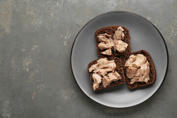 Tasty sandwiches with cod liver on grey table, top view. Space for text