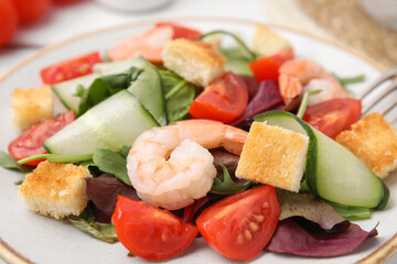 Tasty salad with croutons, tomato and shrimps on table, closeup