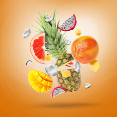 Many fresh tropical fruits falling on orange background