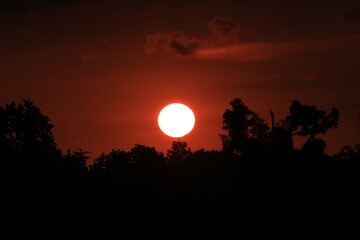Obraz premium photo of the sun setting in a corner of the village with the silhouette of trees