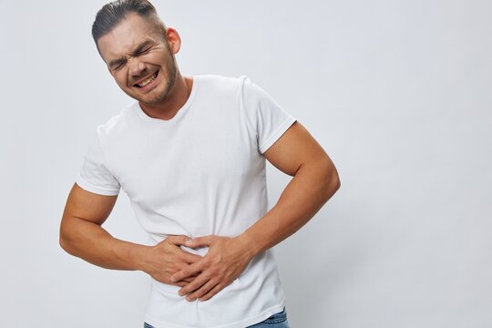 Man abdominal pain, gastritis and appendicitis inflammation, in white T-shirt on white isolated background, copy space