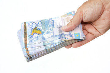 A large amount of money in a man's hand on a white background. A pack of 10,000 Kazakhstani tenge banknotes in a man's hand. The concept of buying for cash, bribery, loan. Transfer of cash.