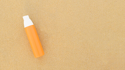 Sunscreen spray in orange bottle on a sandy background. The concept of applying sunscreen during a beach holiday. Layout for adding text, banner, blank for design.