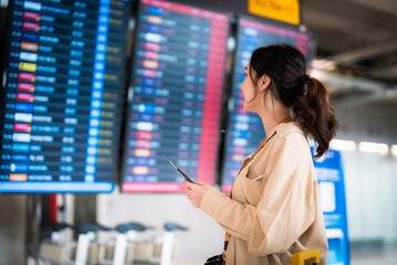 Young asian woman with passport and boarding pass as a hand in international airport looking at the...
