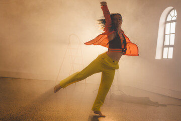 Image of biracial female modern dancer dancing in smoked interior