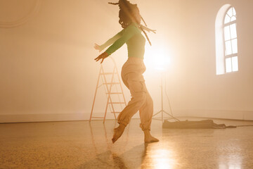 Image of biracial female modern dancer dancing in smoked interior