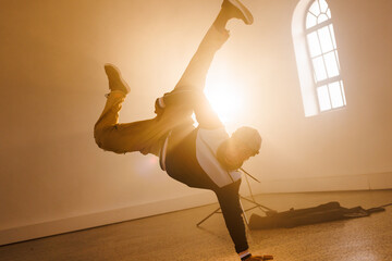 Image of biracial male hip hop dancer dancing in smoked interior
