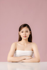Obraz na płótnie Canvas Cosmetics and skin care. Portrait of Asian beautiful woman showing natural clean facial skin isolated on pink background.