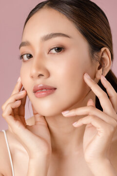 Cosmetics and skin care. Portrait of Asian beautiful woman showing natural clean facial skin isolated on pink background.