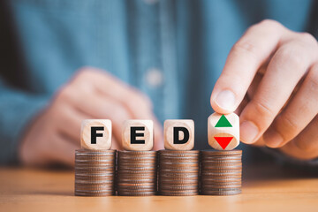 Businessman flipping up and down arrow with FED on coins stacking for Federal reserve increase and decrease interest rate control which effect to America and world economic growth concept.