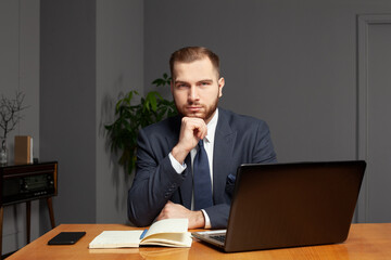 Professional pensive businessman is thinking about work by the laptop in office
