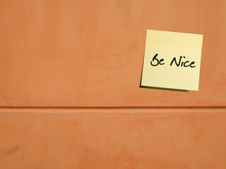 Old wall with text on sticky note BE NICE- concept of treat other people with respect, making others feel good and pave way to good relationship