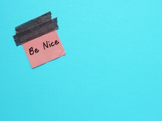 Sticker on blue copy space background with handwriten text BE NICE- self reminder to treat other...