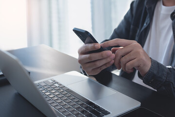 Casual business man, freelancer using mobile phone and online working on laptop computer on table,...