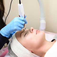 A beautician performs a rejuvenating mesotherapy procedure using dermapen.