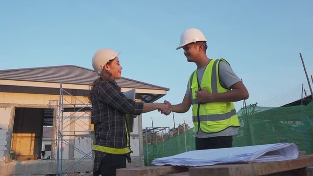 Asia engineers with tanding on construction site, shaking hands.
 Female engineer shakes hands with partner in agreement.