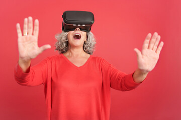 Naklejka premium Surprised mature woman using virtual reality goggles
