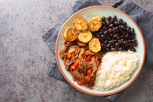 Pabellon Criollo Venezuela's national dish with shredded beef, rice, black beans and fried plantains closeup on the plate on the table. Horizontal top view from above