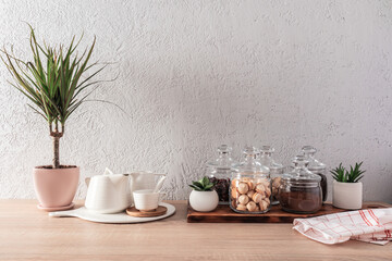 Fototapeta premium kitchen interior , background. glass jars with dry tea, biscuits, coffee beans, white ceramic teapot and cups. Plants. front view.