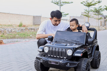 Father having fun with little son, ridingcar toy at the park. 