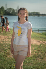 Portrait of a young beautiful girl on the river bank in summer.