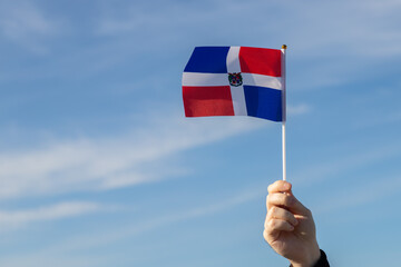 Dominican Republic flag in hand flutters in the wind against the sky, independence national day of...