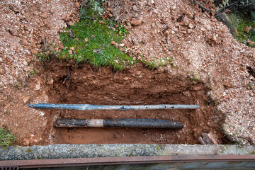 Top view photo shows broken water pipes in a dug hole outdoors.