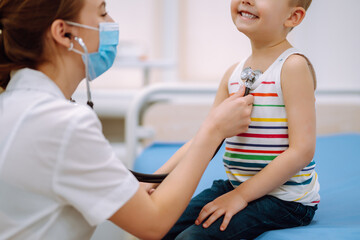 Fototapeta premium Doctor examining a little boy by stethoscope. Сhild's health.