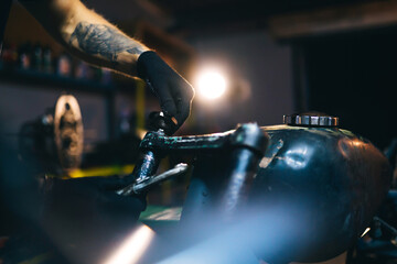 Motorcycle repair. Disassembled motorcycle. The expert works with electric welding of metal. Instruments and equipment.