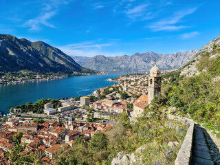 Fototapeta na wymiar Panoramic view from Kotor city walls on Church of Our Lady of Remedy and Kotor bay in sunny summer, Adriatic Mediterranean Sea, Montenegro, Balkan Peninsula, Europe. Fjord winding along coastal towns