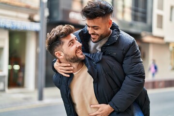 Young couple smiling confident holding boyfriend on back at street
