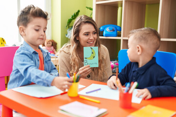 Teacher with boys sitting on table having language lesson at kindergarten