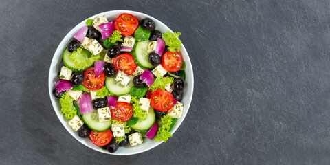 Greek salad with fresh tomatoes olives and feta cheese healthy eating food from above on a slate...