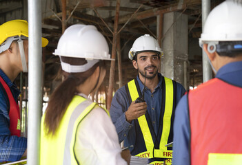 engineer project manager holding walkie talkie talking to team on the building under construction,engineer teams wearing full safety gear while work on height complex and dangerous construction sites