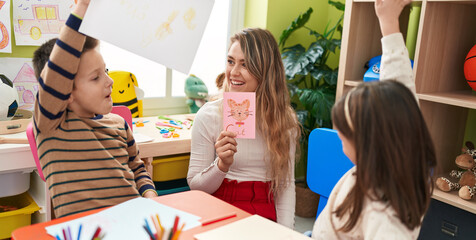 Teacher with boy and girl sitting on table having language lesson at kindergarten