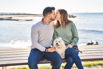 Man and woman holding dog hugging each other kissing at seaside