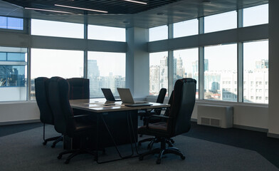 Table and chairs in the interior of a modern office with large panoramic windows against the backdrop of city skyscrapers