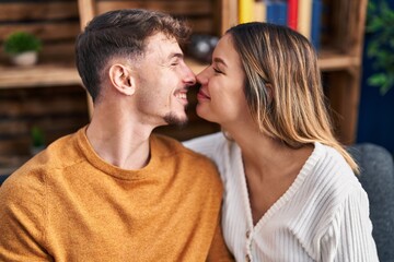 Young man and woman couple hugging each other sitting on sofa at home