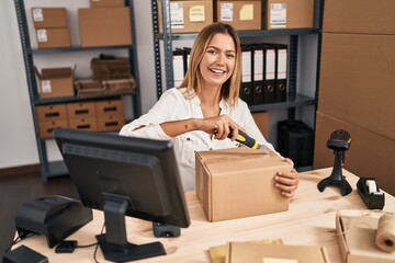 Young hispanic woman ecommerce business worker unboxing package at office