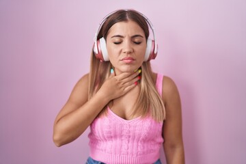 Young blonde woman listening to music using headphones touching painful neck, sore throat for flu, clod and infection