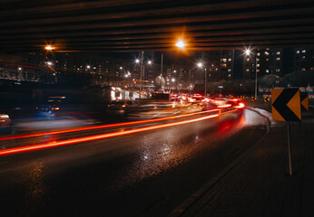 Fototapeta na wymiar Evening car traffic in a big city. Cars in motion and standing in traffic jams. Long exposure exposure and headlight trails