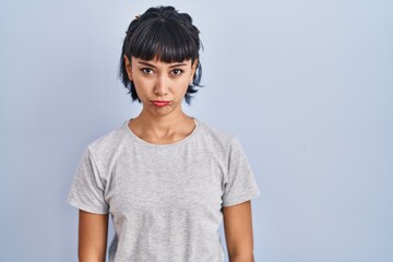 Young hispanic woman wearing casual t shirt over blue background depressed and worry for distress, crying angry and afraid. sad expression.