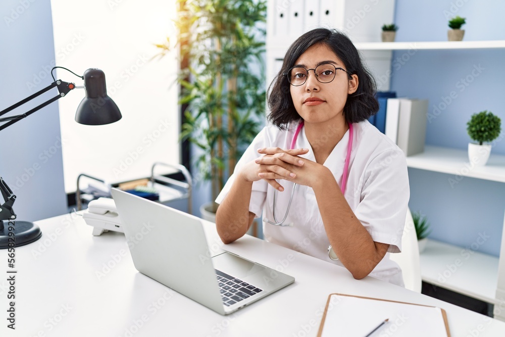 Poster Young latin woman wearing doctor uniform working at clinic