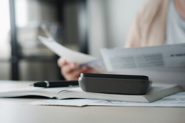 Woman calculating money to save for household expenses in money coin jar
