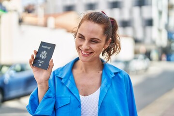 Young woman smiling confident holding united states passport at street