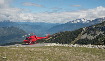 Red helicopter in on Blackcomb mountain in whistler, Canada during summer on a sunny day with...
