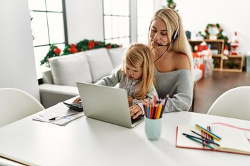 Mother and daughter teleworking sitting by christmas tree at home