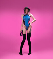 sexy gamer girl in a revealing bright bodysuit and gaming headset on a pink background
